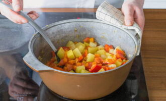 Em seguida, adicione as batatas e as cenouras e continue fritando por 10 minutos. Depois disso, adicione os pimentões e os tomates, mexa e cozinhe por mais 5 minutos.