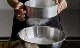 Com cuinar el pastís de pa de cireres al forn? Tamisar la farina en un bol profund i barrejar-la amb el sucre en pols. 