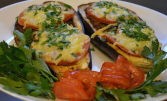 During this time you need to have time to prepare the cheese. Grate the required amount on a grater, preferably a coarse one, into a separate container. After 15 minutes, remove the baking sheet with eggplants from the oven and sprinkle the dish with cheese. Bake for another 15 minutes.