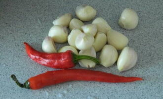 We clean the garlic cloves from the husks, and the chili peppers from the stalks.