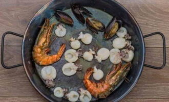 Heat a frying pan with olive oil. We put king prawns and other seafood in it. Fry them for 2-3 minutes. Then place the mussels on a plate for a while.