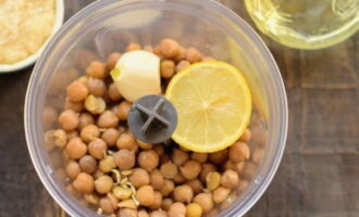 Next, add the boiled chickpeas, garlic, salt and cumin into the blender. Add the remaining oil and lemon juice.