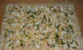 Next, lay out the eggs, cheese, herbs and crab sticks. Add salt, pepper and chopped garlic to the filling. Roll the workpiece into a roll.