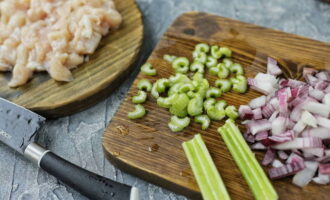 Separate the chicken fillet from the bone, clean it of white films and fat and cut it into small cubes of the same size. We peel the onion and finely chop it, peel the celery and also chop it.