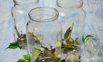 Wash and sterilize the seaming jars. Place dill umbrellas, bay leaves, peppercorns, garlic cloves and hot pepper rings into jars.