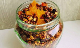 Thêm quả mơ khô, mận khô, nho khô và quả nam việt quất cắt nhỏ vào, trộn và chuyển granola vào hộp bảo quản tiện lợi.