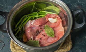 How to cook delicious soup with canned beans? Place a piece of pork in a saucepan. We also add spices and herb stems. 