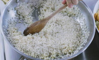 Pour the rice into the saucepan and, stirring constantly, keep it on low heat for one or two minutes so that the grains are soaked in the aromatic oil.