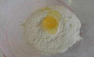 How to make classic ravioli at home? Sift flour with a pinch of salt into a deep bowl. Break a chicken egg here and add a spoonful of oil.