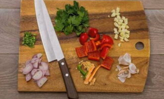 Cut the garlic into small cubes. We wash the bell pepper, peel it and cut it into large pieces. Cut the shallots into half rings. Cut off the parsley stems and chop them.