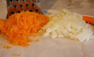 Now let's prepare the base for the soup. First, peel the onion and try to chop it as finely as possible. Now it’s the carrots’ turn: they need to be cleaned and washed with running water to remove any dirt. Grind the vegetable on a coarse grater. 