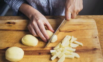 Now it's the potatoes' turn. Using a sharp knife, cut off the peel from all the tubers and wash them, chop the potatoes into bars. Pour the ingredient into the pan with the broth.Next we add the fried onions and carrots.