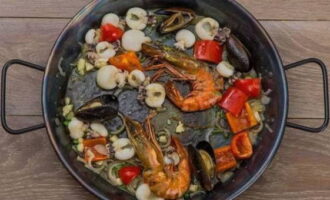 Next, add bell peppers and onions to the pan. Mix everything thoroughly and fry for another 2 minutes, then add the garlic and parsley stems. Fry everything for a minute and transfer the mussels to a plate.