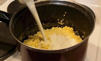 Pour hot milk into the millet, mix everything well and reduce the heat to low.