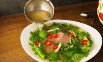 Pour all the ingredients into warm rich broth and serve. Be sure to place the remaining herbs, lime, and fish sauce on a flat plate so that everyone can adjust the dish to their own taste. 