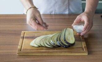 Læg aubergineskiverne og enderne på bagepapir drysset med vegetabilsk olie, salt let og drys olie på toppen igen. 