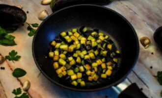 Opvarm en stegepande med vegetabilsk olie. Læg færdigskårne aubergineterninger her og salt dem efter smag. Steg produktet, indtil det er gyldenbrunt.