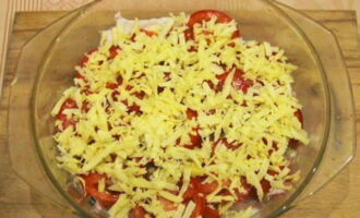 Next, lay out thin slices of tomatoes and sprinkle them with grated cheese.