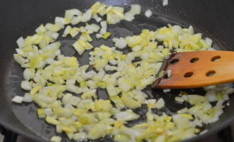 At this time, prepare the filling with which we will stuff the zucchini. Peel the onion and garlic and chop finely. Heat a small amount of vegetable oil in a frying pan and fry the vegetables in it until soft, stirring occasionally.