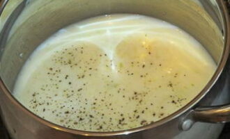 Stir ground black pepper and chopped garlic into milk.