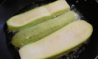 Versare l'olio nella padella. Per prima cosa devi scaldarlo sul fornello per un paio di minuti. Disporre le fette di zucchine sul fondo del contenitore e friggerle su entrambi i lati finché non diventano dorate e i piatti si ammorbidiscono.