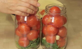 Seterusnya, letakkan tomato dengan lubang menghadap ke atas. Oleh itu, kami menggantikannya dengan dill, bawang putih dan saderi sehingga balang penuh.