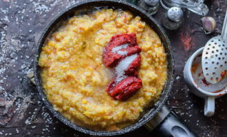 Trasferisci la massa risultante nella padella. Aggiungere olio vegetale, concentrato di pomodoro, pepe nero macinato, sale e zucchero semolato. Mescolare, coprire con un coperchio e cuocere a fuoco lento per trenta minuti a fuoco basso. Mescolare di tanto in tanto. A fine cottura aggiungere l'essenza di aceto e mescolare.