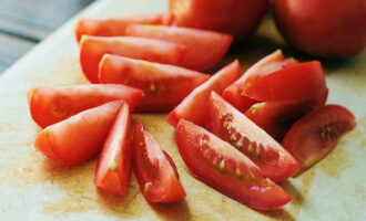 Lave os tomates. Limpe o vegetal e corte-o em fatias pequenas. Durante o processo de corte, retiramos os pontos de fixação dos talos. Como alternativa, coloque uma pequena quantidade de recheio (uma colher de chá) em cada fatia, coloque uma rodela de tomate e um raminho de ervas por cima (primeiro lavamos o cacho e desmontamos em raminhos). 