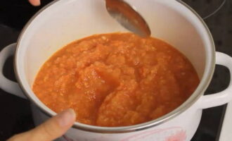 Then transfer these chopped vegetables into a saucepan with a thick bottom or non-stick coating and place on the stove, turn on medium heat. After the mixture begins to boil, cook it over low heat for 20 minutes, stirring occasionally with a spatula so that it does not burn. Towards the end of cooking, add salt to the adjika to your taste, add sugar and add two tablespoons of tomato paste for a brighter color.