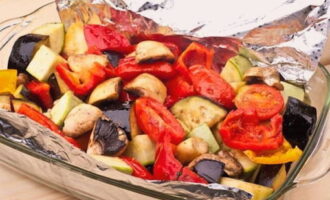 Cubra una fuente para horno con papel de aluminio y extienda las verduras.