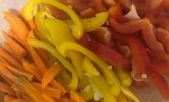 While the chicken is stewing, chop the peppers and carrots into thin strips. You can take two colors of pepper: half red and half yellow.