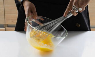 Now we need 3 eggs. Drive one egg into a deep bowl, not completely, but only the yolk. Beat 2 more eggs completely into the yolk. Beat the eggs until light foam forms. You don't have to do this with a mixer. A whisk is enough.