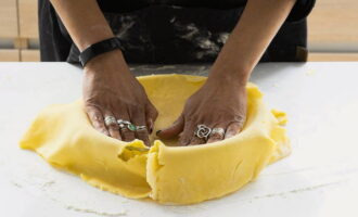 Take a round baking dish and grease it with a small piece of butter. Place the dough into the container, trying to press it as tightly as possible to the bottom and sides.