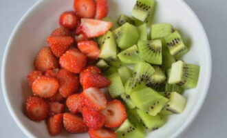 Let's start cutting. We peel the kiwi and cut it together with the strawberries. Place in a deep plate.