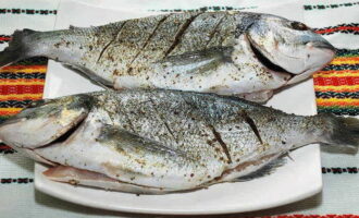 Vi laver lavvandede snit (3-4 centimeter) på siderne af fisken. Vi behandler doradoen inde og ude med en blanding af urter og krydderier.