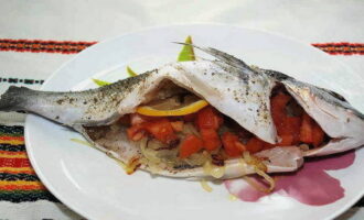 Add them to the onion, add salt, mix and simmer under the lid for a couple of minutes. Fill the inner cavity of the fish with onion and tomato filling. Wash the lemon and cut 2-4 slices from it. We put them inside the body of the fish.