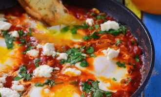 Sprinkle the shakshuka with salt and pepper. Make sure that the whites turn white and the yolks remain runny. Wash the greens and chop them as desired. Sprinkle over the finished shakshuka. Serve the dish on preheated plates. If you put the dish on cold plates, it will fall off and will not be as tasty.