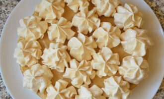 Sau đó đặt meringue nhỏ gọn lên trên lớp kem thành một lớp. Nên làm 3-4 lớp meringue nên tách ngay ra. Phủ toàn bộ meringue bằng kem ở phía dưới. Chúng tôi xếp chúng thành một đống, và cũng lấp đầy khoảng trống giữa các bánh trứng đường bằng kem.