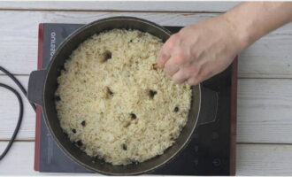 After 10 minutes, tap on the wall of the cauldron with a slotted spoon, and if the sound is dull, then make punctures in the pilaf with a stick to the bottom of the cauldron to remove steam through them.