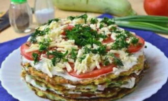 Plaats de pannenkoek opnieuw in de volgende laag, bestrijk hem met zure room en knoflooksaus, tomaten en een kleine hoeveelheid geraspte kaas. Herhaal dit totdat de courgettekoekjes en andere ingrediënten op zijn.