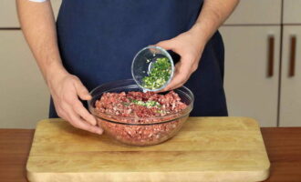 Finely chop the green onions and garlic cloves with a knife. Remove seeds from chili peppers and chop finely. Add the crushed spices to the minced meat and mix.