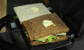 Place the sandwiches in a multi-baker and place a small piece of butter on top of each sandwich for a creamy taste.