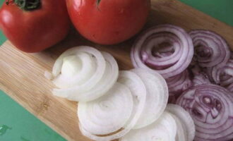 Two types of peeled onions are cut into thin half rings or rings, tomatoes - into cubes.