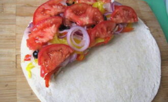 Next add onions, olive rings and tomato cubes. The tortilla is carefully folded in half. 