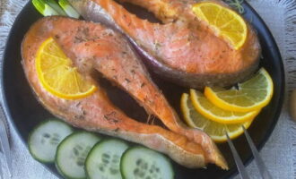 Bake the fish in the oven for 25 minutes. Then carefully remove the foil and serve the salmon steaks with lemon wedges and fresh herbs.