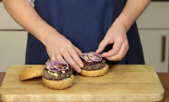 Cut the buns in half and fry in a dry frying pan on the cut side. Place a lettuce leaf and a cutlet on the bottom of the bun, pour ketchup and mustard over it. Add red onion rings, tomato and cucumber slices.