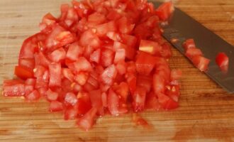 Vi vasker tomaterne og fjerner skindet: vi skærer i toppen af ​​tomaterne i form af et kryds og skolder tomaterne med kogende vand, efter et par minutter vil skindet let skalle af frugtkødet. frugt. Skær tomaterne i tern (fjern kernerne). 