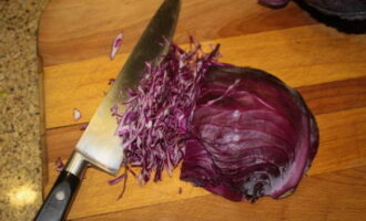 How to make red cabbage salad? We start by preparing the cabbage. We rinse it thoroughly under warm running water, then dry it on a paper towel, transfer it to a cutting board and cut into thin strips.