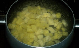 A sopa de queijo clássica é muito fácil de fazer. Despeje a água em uma panela grande e leve ao fogão. Agora lavamos as raízes e cortamos a casca com uma faca. Lave as batatas o máximo possível em água corrente e corte-as em cubos médios. Coloque em uma panela com água.