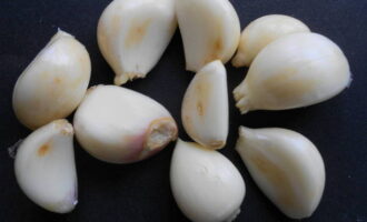 Take a head of garlic and separate it into cloves. Then we free each clove from the husk and rinse in running water. Place half of the cloves on a plate: we will need them in the process of stuffing the bird.